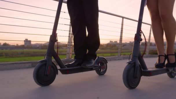 LENS FLARE : Des collègues en tenue de travail montent des scooters électriques pour travailler au lever du soleil. - Séquence, vidéo