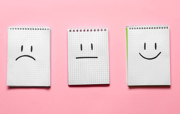 Zápisníky s kreslenými smutnými, šťastnými a neutrálními tvářemi na barevném pozadí - Fotografie, Obrázek
