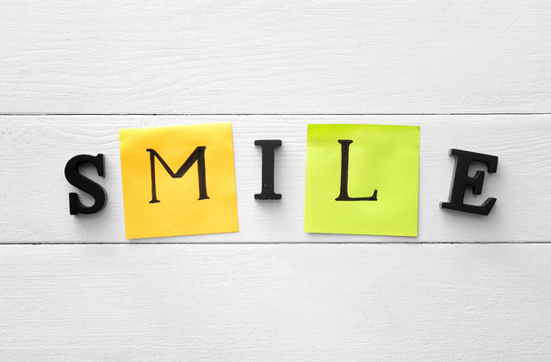 Woord SMILE op witte houten achtergrond - Foto, afbeelding