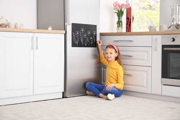 Kleines Mädchen zeichnet auf Kreide in Küche - Foto, Bild