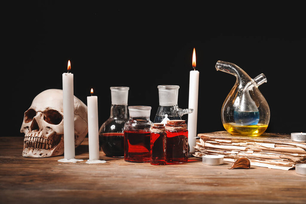 Potions, human skull, old book and candles on alchemist's table - Photo, Image