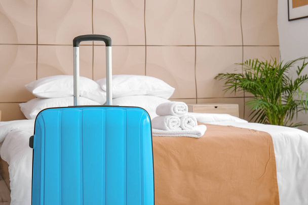 Βαλίτσα κοντά στο κρεβάτι στο δωμάτιο του ξενοδοχείου - Φωτογραφία, εικόνα