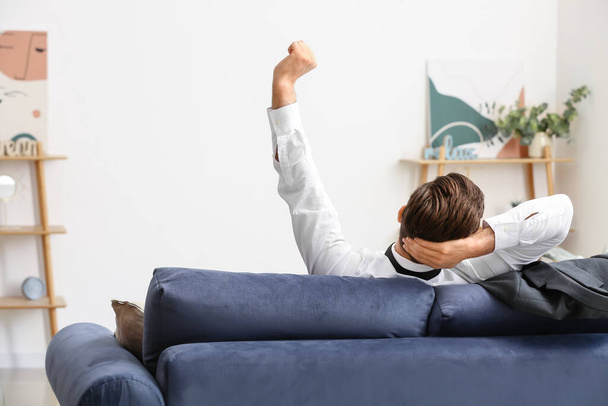 Бизнесмен отдыхает дома на диване после долгого рабочего дня
 - Фото, изображение