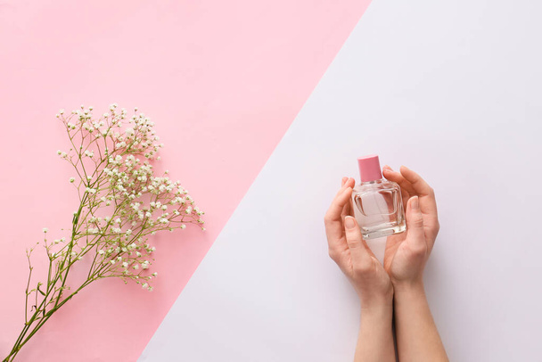 Female hands with perfume and flowers on color background - Photo, Image