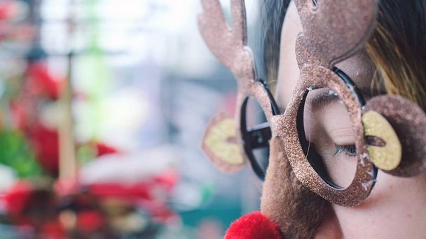 Close up jonge vrouw dragen grappig kerstfeest hert bril met rode neus.. - Foto, afbeelding