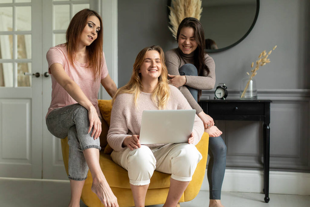 a group of girlfriends communicate with a friend via a video conference on a laptop. Friendship - Zdjęcie, obraz