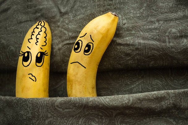 Twee bananen, man en vrouw, op donkere lakens. De ene is beledigd, de andere wil het goedmaken. Familie ruzie, ruzie. De foto is gemaakt door de auteur. - Foto, afbeelding