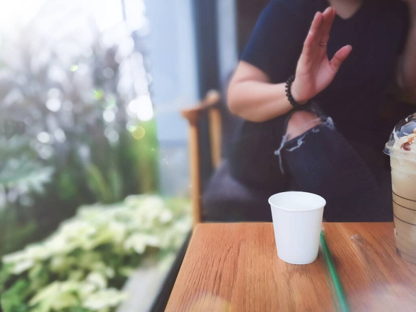 Close-up weiße Tasse auf dem Tisch mit junger Frau sitzt im Café-Restaurant im Gespräch und Kaffee trinken, Erfrischungsentspannungskonzept. - Foto, Bild