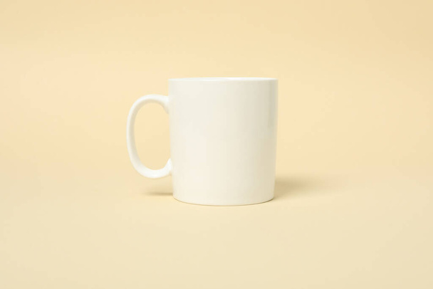 Empty white cup on beige background, space for text - Zdjęcie, obraz