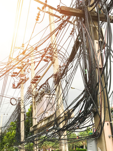 The chaos of cables and wires on an electric pole.Messy wires attached to the electric mast. Many electrical cable in Bangkok, Thailand, concept of electricity. - Photo, Image