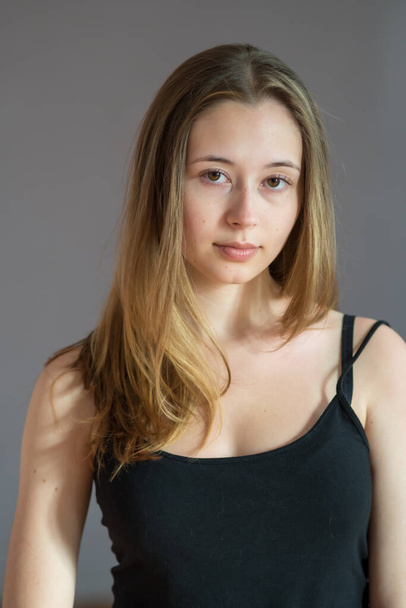 Portré egy vonzó tizenéves lány visel camisole pózol nézi a kamera szürke háttér - Fotó, kép