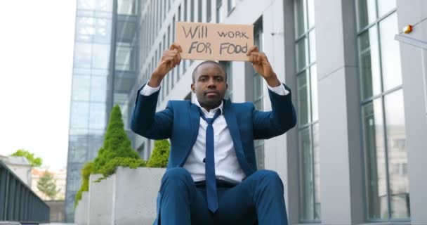 Retrato de un joven afroamericano demostrando póster con palabras Trabajará por la comida. Activista masculino mostrando junta con la búsqueda de anuncio de trabajo. Solitario protestando. Después del bloqueo el desempleo
 - Metraje, vídeo