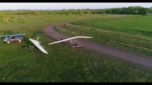 Hang πτήση ανεμόπτερο στο χρόνο ηλιοβασιλέματος πάνω από πράσινο και κίτρινο φρέσκα πεδία άνοιξη. Αεροφωτογραφία πάνω. Που λαμβάνονται με drone. - Πλάνα, βίντεο
