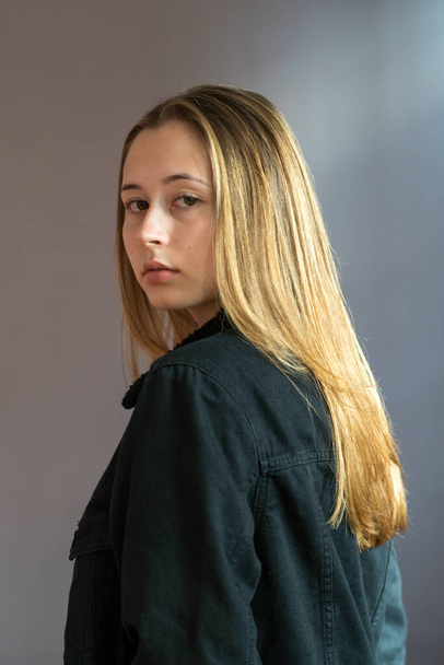 Halbprofil-Porträt eines hübschen Teenagers mit langen natürlichen blonden Haaren und glatter Haut, der in die Kamera blickt. Studioaufnahme - Foto, Bild