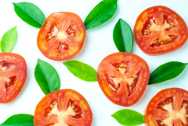 Wzór świeżego soczystego pomidora w plasterkach z zielonymi liśćmi na białym tle. - Zdjęcie, obraz