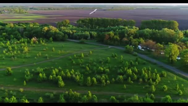 Hang πτήση ανεμόπτερο στο χρόνο ηλιοβασιλέματος πάνω από πράσινο και κίτρινο φρέσκα πεδία άνοιξη. Αεροφωτογραφία πάνω. Που λαμβάνονται με drone. - Πλάνα, βίντεο