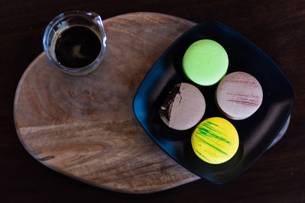 Top view of Sweet and colourful french macaroons or macaron cake and a glass of coffee on wooden board and copy space, Dessert. - Fotó, kép