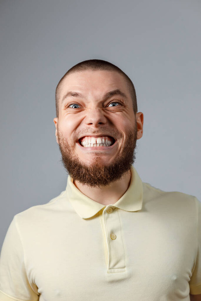 Close-up portrait of a young happy man in a yellow T-shirt, emotions on a gray background. isolated. - Valokuva, kuva