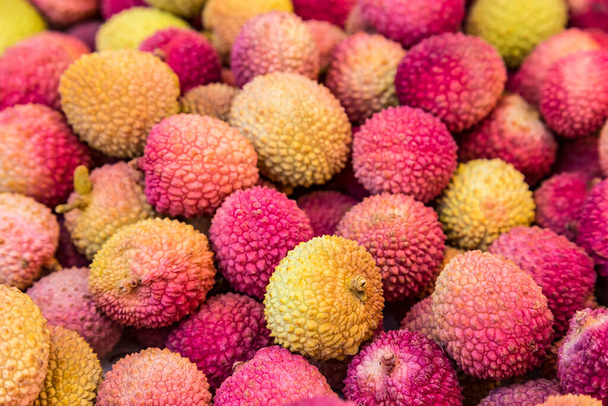 Fresh red and yellow litchi fruits on the market, also known as lichee, lychee, or lichi, Litchi chinensis natural food background. - Foto, immagini