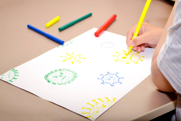 Çocuk elinde sarı keçeli kalem tutuyor ve kağıda virüs çiziyor. - Fotoğraf, Görsel