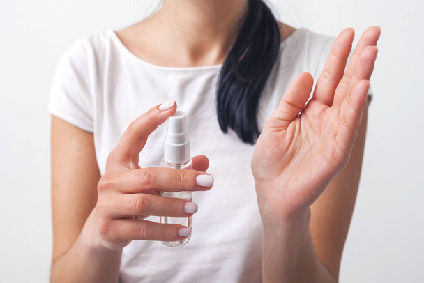 Händedesinfektion. Lady 's Hand nimmt Alkohol-Desinfektionsspray auf ihre Hände. um eine Virusepidemie zu verhindern. Vereinzelt auf weißem Hintergrund. Grippevorbeugung Hände gründlich reinigen und desinfizieren. - Foto, Bild