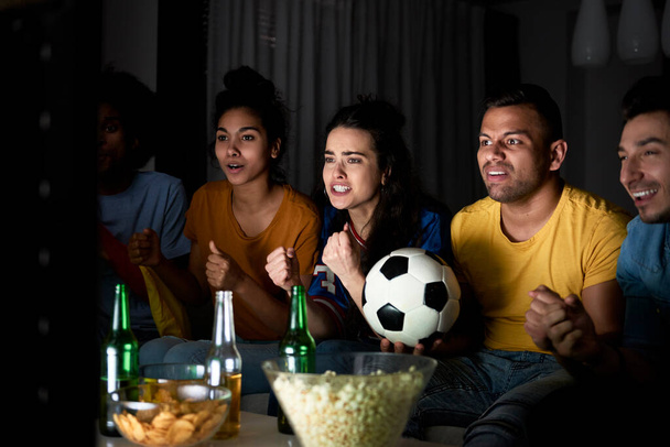 Grupo de amigos animando en frente de la televisión por la noche
 - Foto, Imagen