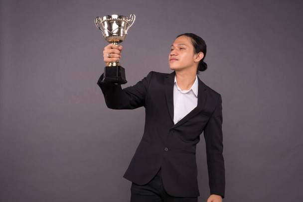 Un jeune homme d'affaires tenant un trophée d'or et célébrant son archivage
. - Photo, image