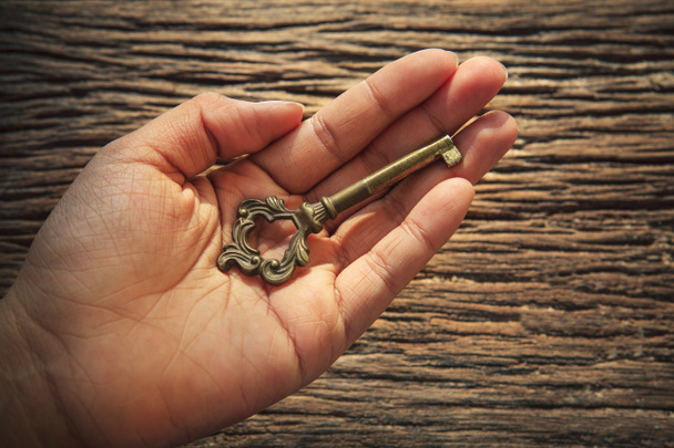 Abstrato de chave de metal na mão esquerda contra texturizado de madeira de casca
 - Foto, Imagem