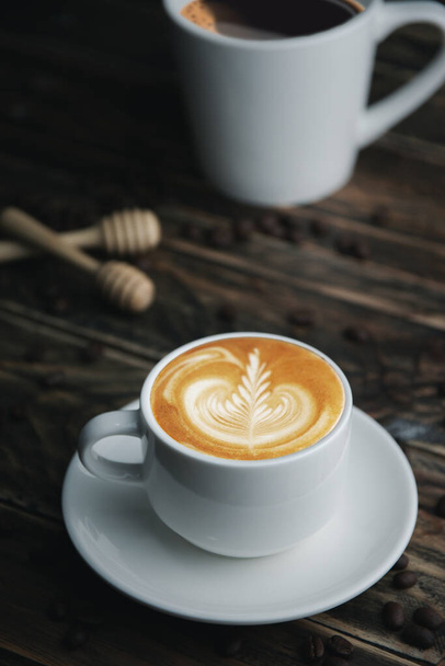 Deux tasses de café sur une table en bois avec une cuillère et des grains de café dans l'image
. - Photo, image