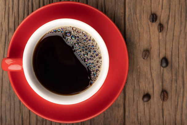 Top view of red cup of black coffee on wooden table with copy space. - Photo, Image