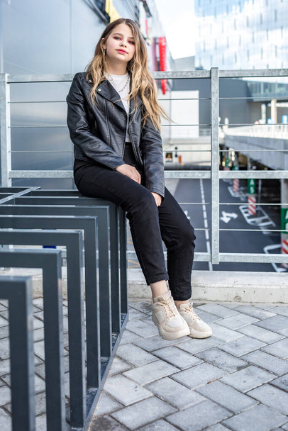 young blonde schoolgirl in black leather jacket posing in the parking lot - Foto, Bild