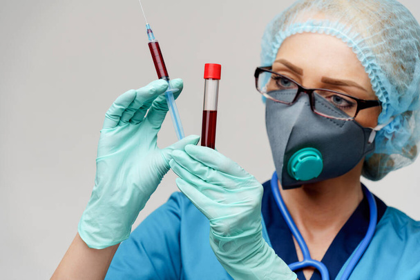 medical doctor nurse woman wearing protective mask and gloves - holding virus blood test tube and syringe - Foto, afbeelding