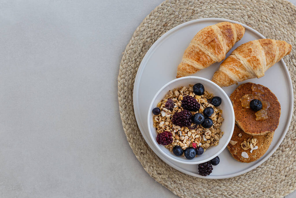 Вид сверху на вкусный завтрак. Гранола с ягодами, круассаном
 - Фото, изображение