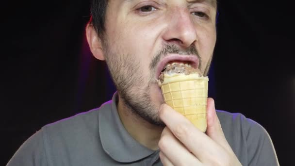 Zbliżenie portret głodnego brodatego mężczyzny jedzącego lody - Materiał filmowy, wideo