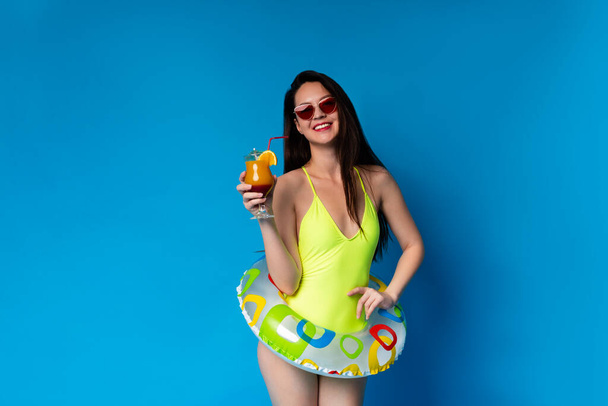 Summer Chil. Positivo asiático chica posando con cóctel y natación anillo
 - Foto, imagen