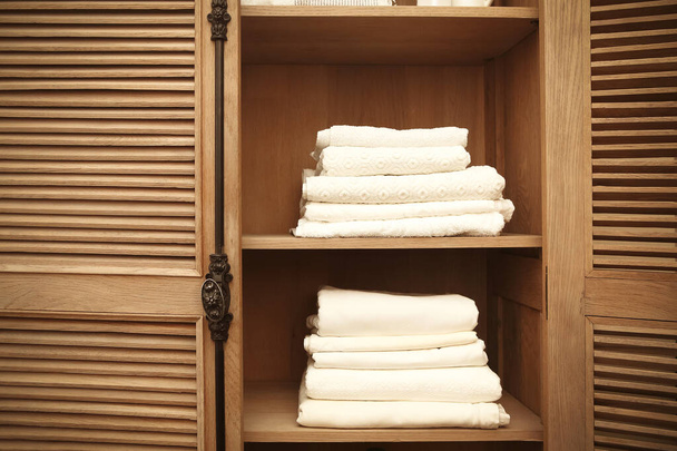 Montones de toallas suaves blancas limpias en armario retro en la habitación, primer plano
  - Foto, Imagen
