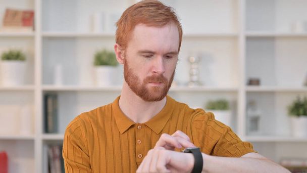 Portrait of Serious Redhead Man using Smart Watch  - Photo, Image