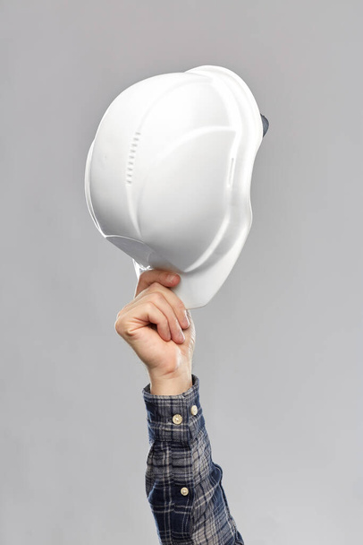 close up of builders hand holding helmet - Φωτογραφία, εικόνα