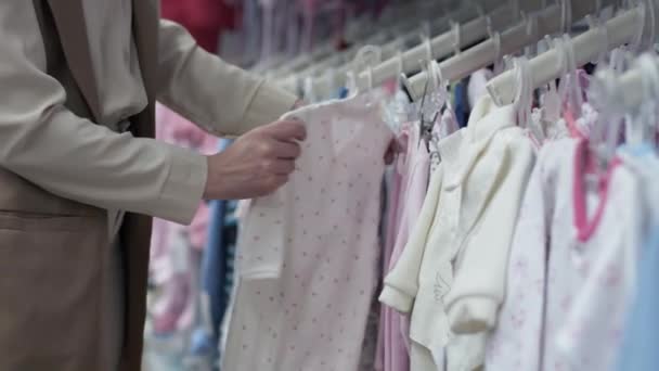 γυναίκα γονέας αγοράζει πλεκτά για το παιδί της σε ράφια καταστημάτων, close-up - Πλάνα, βίντεο