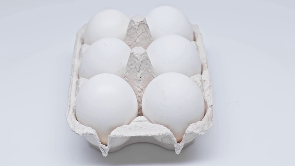 Περιστρεφόμενα αυγά σε χαρτόκουτο σε λευκή επιφάνεια - Πλάνα, βίντεο