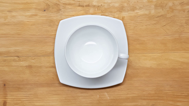 Top view of man putting cup and saucer on wooden surface - Footage, Video