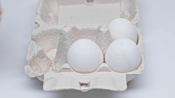 Oříznutý pohled na člověka, jak dává vejce do nádoby na bílém povrchu - Záběry, video