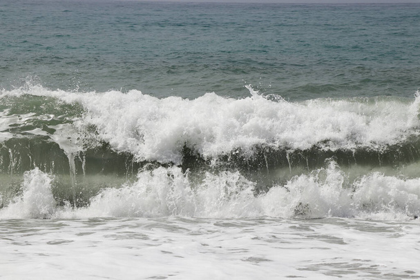 Splash van zeewater na het raken van een rotsachtige klif in het zuidwesten van Cyprus in de buurt van de stad Paphos. Stormachtige en gevaarlijke situatie. Enorme massa 's water. Lawinezee. De vloed komt eraan.. - Foto, afbeelding