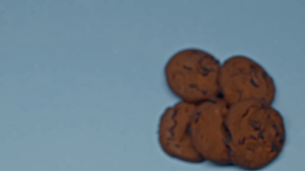 Slow motion of man taking glass of milk near cookies on blue surface - Filmagem, Vídeo