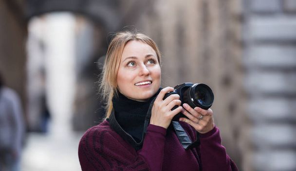 Happy smiling girl taking picture with camera in the town  - Fotografie, Obrázek