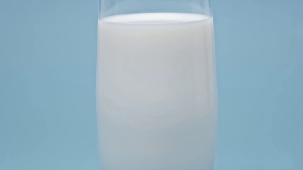 Close up view of glass of milk on blue surface - Záběry, video