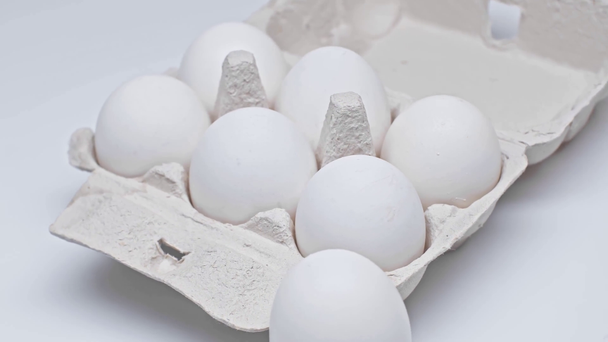 Jaja wirujące w opakowaniu tekturowym na białej powierzchni - Materiał filmowy, wideo