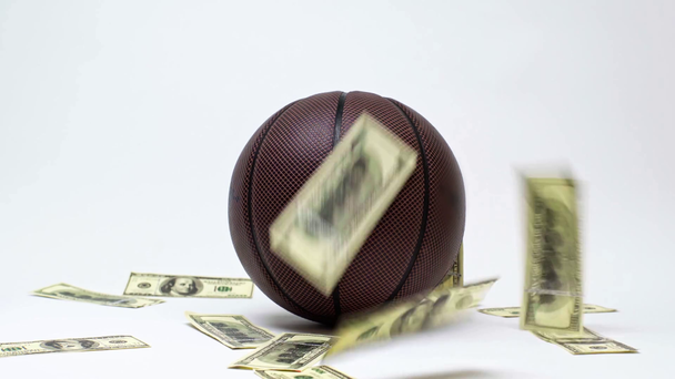 Dollar-Banknoten fallen in der Nähe von Basketball auf weiß, Online-Wettkonzept  - Filmmaterial, Video