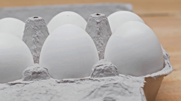 Close up view of eggs in cardboard box on wooden surface - Séquence, vidéo