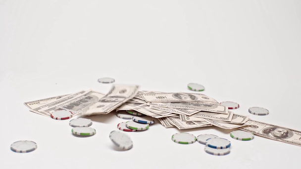 poker žetony a dolary padající na bílé, on-line sázení koncept  - Záběry, video